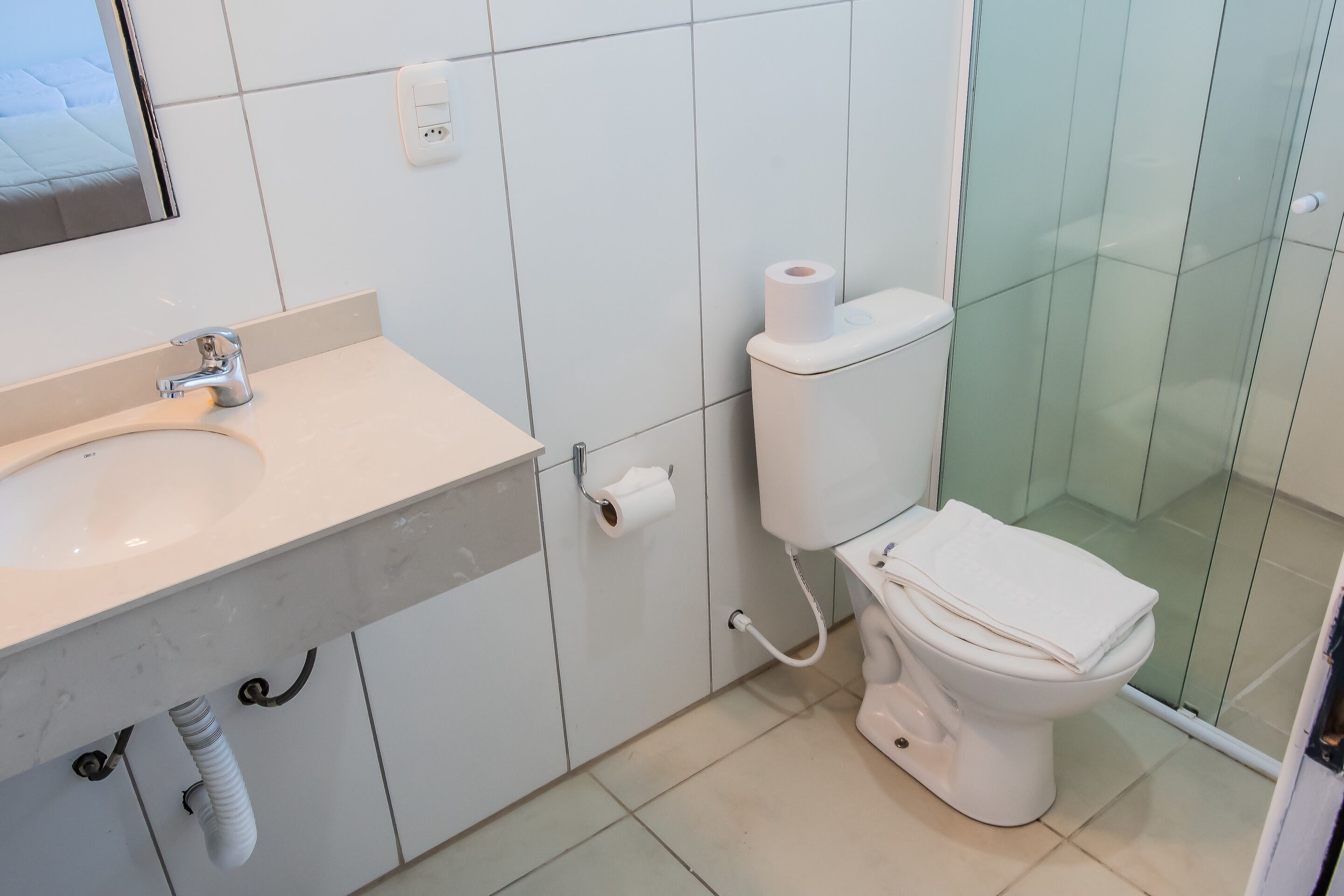 A bathroom with a white sink, toilet, and glass shower enclosure.