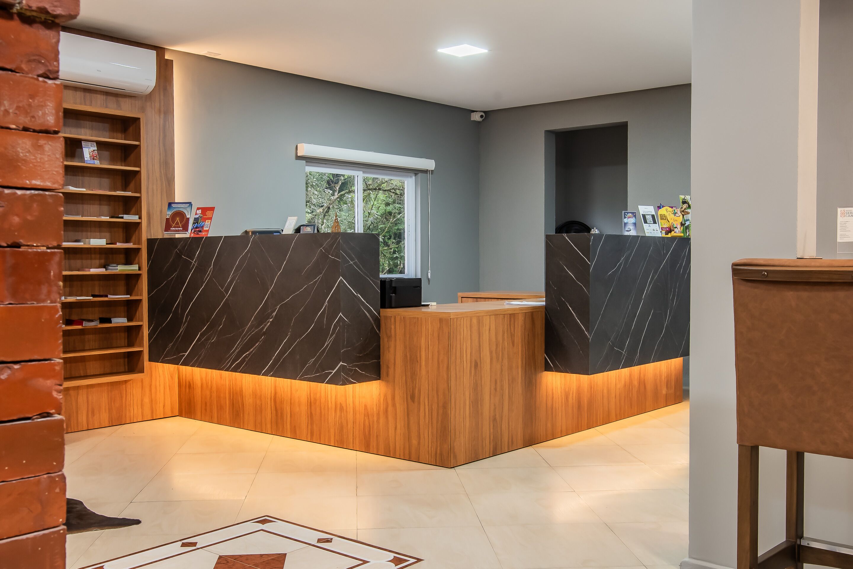 Una zona de recepción con un mostrador de madera, detalles de mármol y una pared de ladrillo.