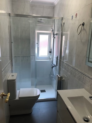 Une salle de bain moderne avec une douche à parois de verre, des toilettes et un lavabo.