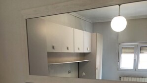 A bathroom with a white vanity, a mirror, and a light fixture. - Apartment near the Sardinero (Santander)
