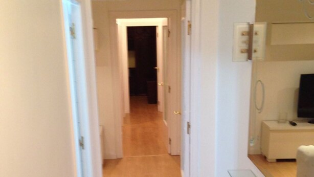 A narrow hallway with wooden flooring and white walls, leading to a dark room at the end. - Apartment near the Sardinero (Santander)