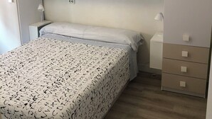 A bedroom with a bed, a wardrobe, and a nightstand. - Apartment near the Sardinero (Santander)