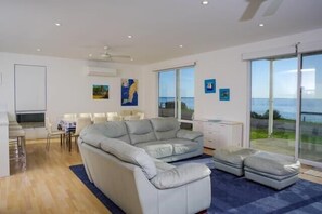 Relax in this stylish living room with a large L-shaped sofa and sliding glass door leading to a balcony with a sea view.