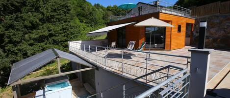 Une terrasse extérieure moderne avec une piscine, des chaises longues et une structure en forme de cabane en bois.
