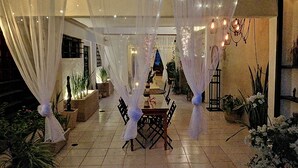 An indoor dining area with a table and chairs, draped with white curtains, and surrounded by potted plants. - Mi Ca-Sa En Mérida (Mérida)