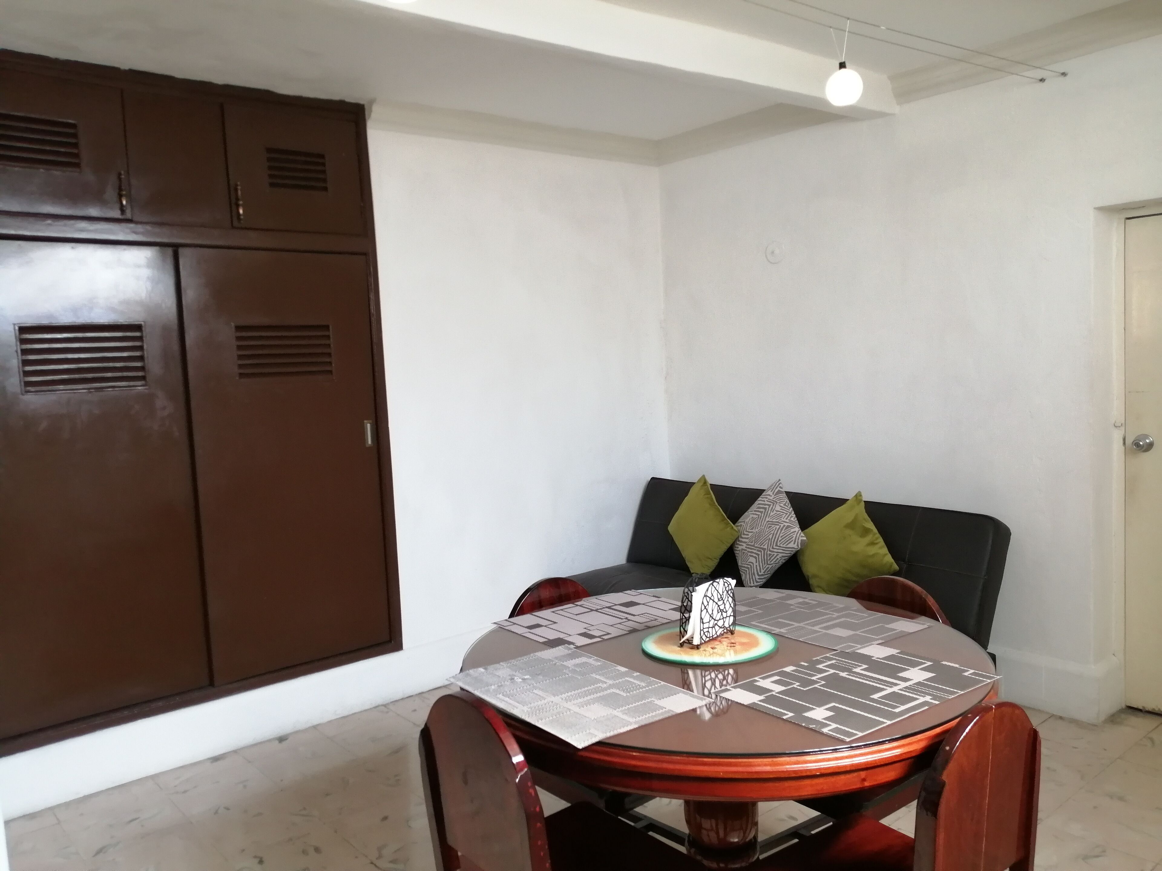 A dining area with a round table, chairs, and a cabinet.