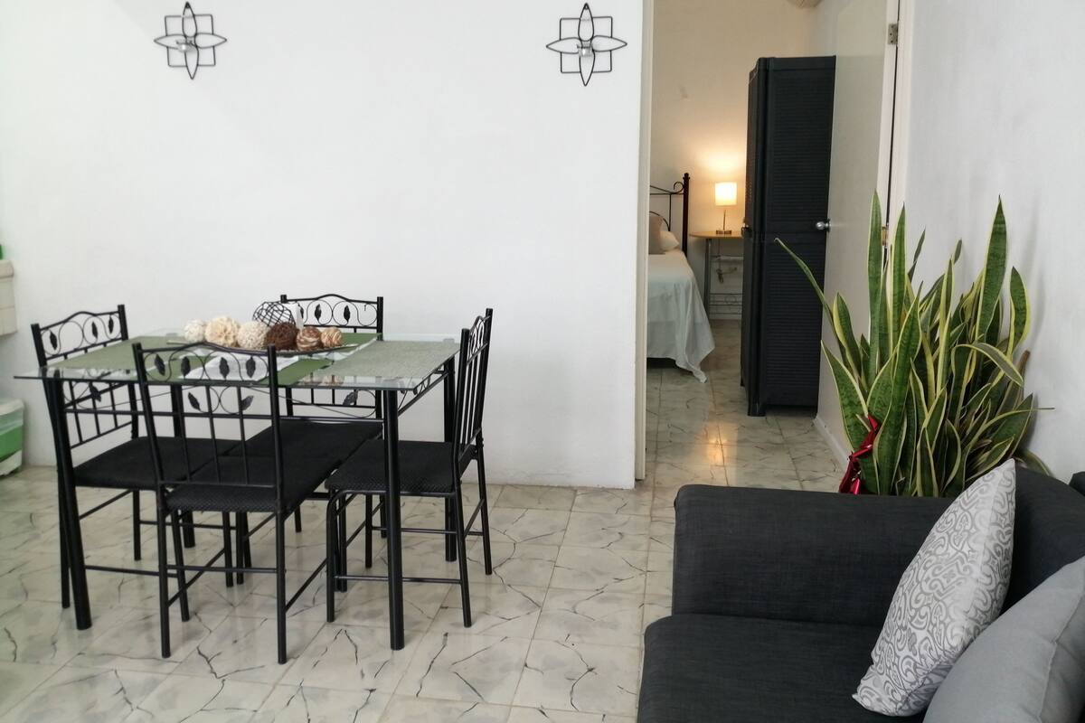 Un coin repas avec une table et des chaises, un canapé et une plante en pot.