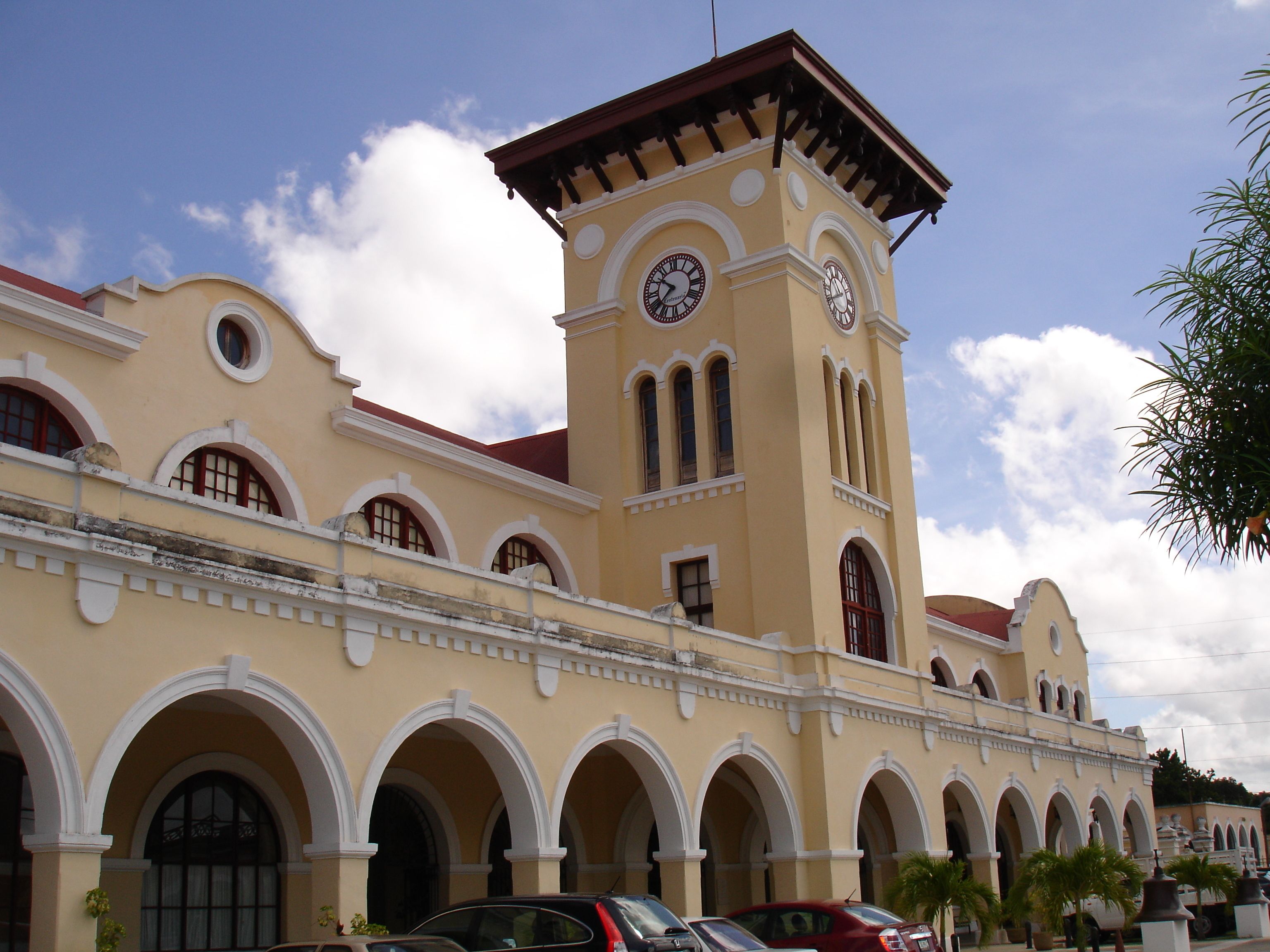 A building with a clock tower, multiple arches, and a red roof.