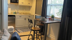 A compact living space with a kitchenette, a dining area with stools, a sofa, and a coffee table. - Heart of Wellington  (Wellington)