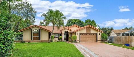 A single-story house with a tiled roof, a front garage, and a well-maintained lawn.