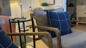 A living room with a sofa, a coffee table, and a lamp. There is a painting on the wall and a sign that reads "HOME sweet HOME". - Heart of Wellington  (Wellington)