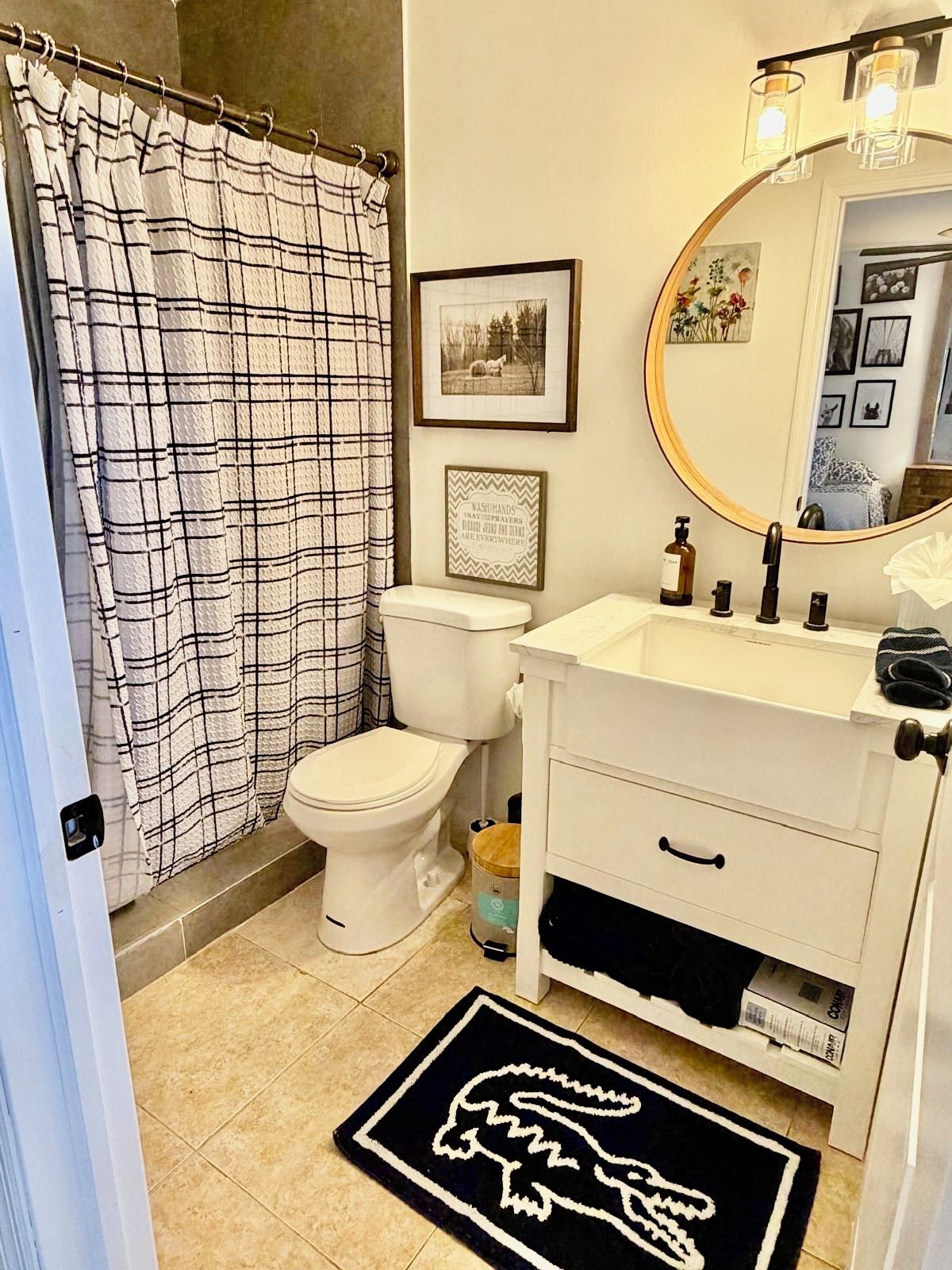 A bathroom with a white toilet, a white sink with a mirror above it, and a black and white checkered shower curtain.