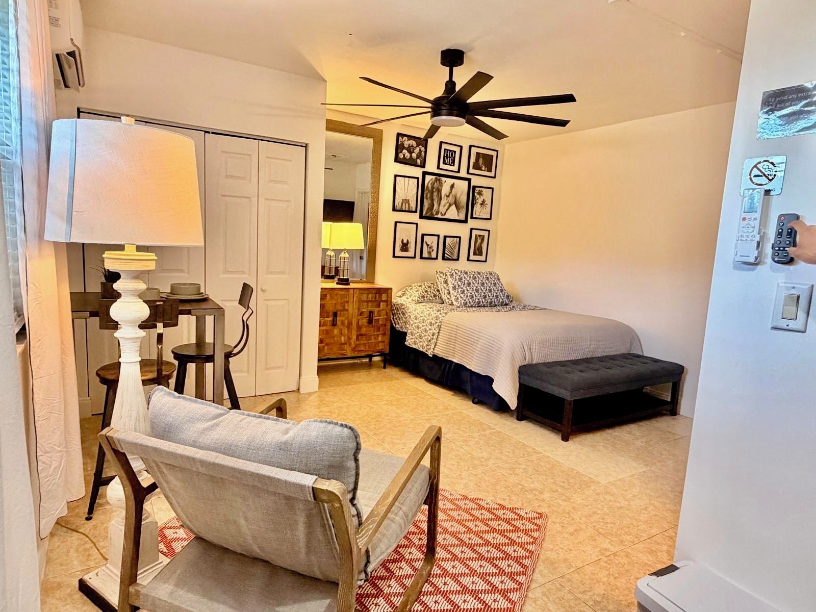 A bedroom with a bed, bedside table, lamp, and a ceiling fan.