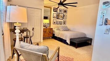 A bedroom with a bed, bedside table, lamp, and a ceiling fan.