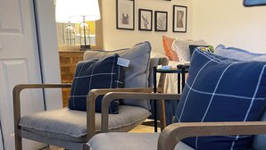 A living room with two grey armchairs, a patterned rug, and a wall decorated with framed pictures. - Heart of Wellington  (Wellington)