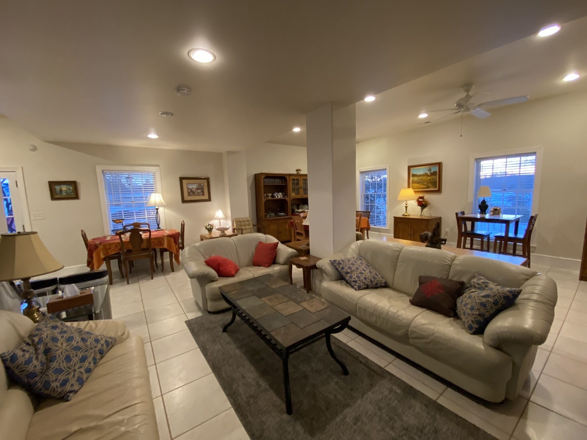 A spacious living room with a sofa, armchairs, a coffee table, and a dining area with a table and chairs.