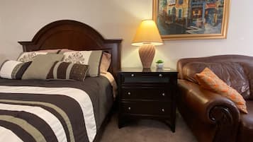 A neatly arranged bedroom with a bed, bedside table, lamp, and a painting on the wall.