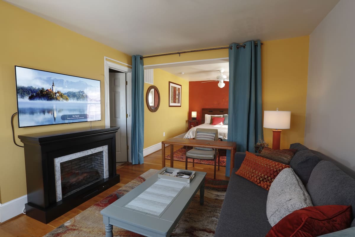 A living room with a fireplace, a television, a sofa, and a dining area.