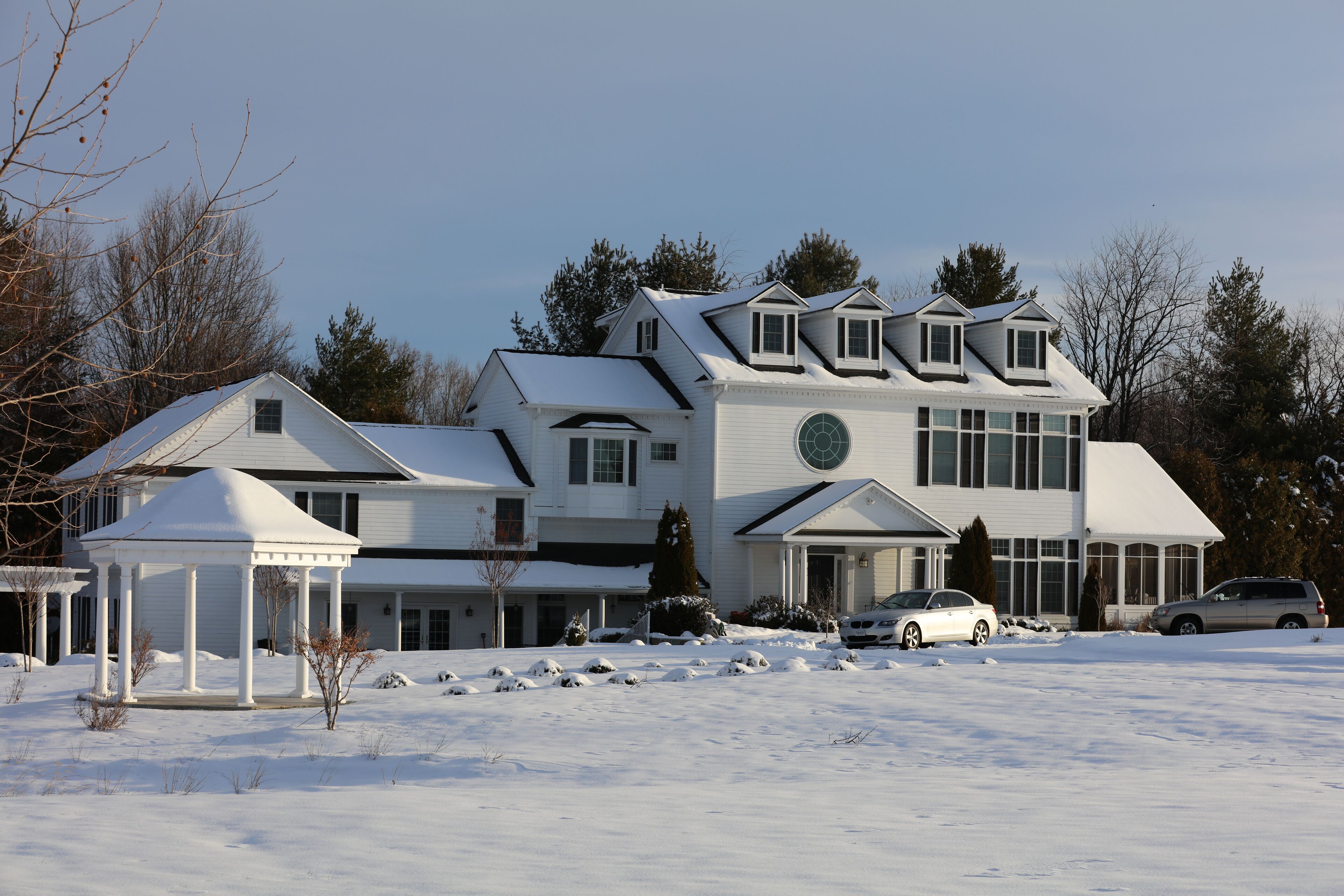 Une grande maison à deux étages, dotée d’une façade symétrique, d’une fenêtre circulaire au centre et d’un porche abrité.
