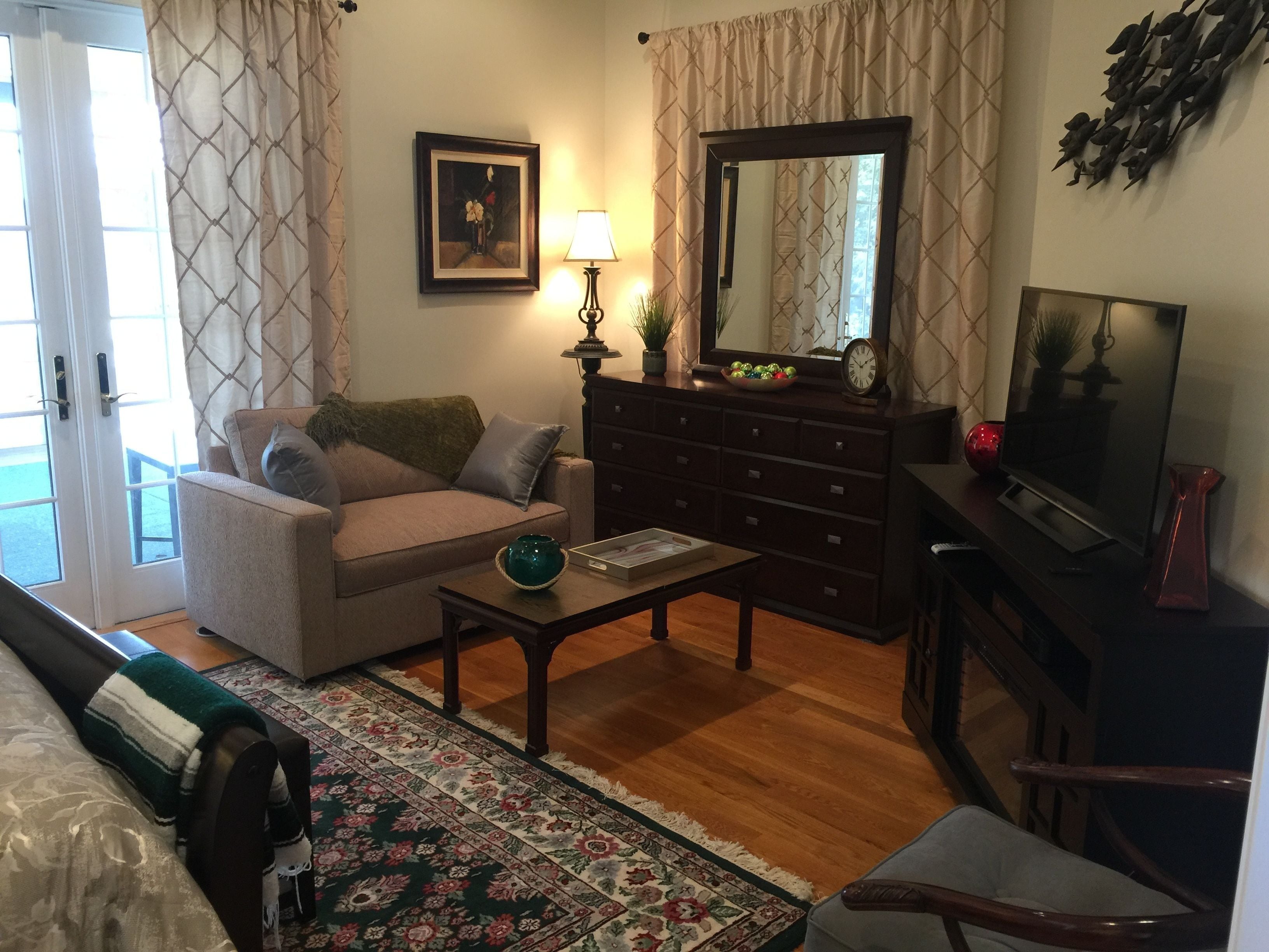 A living room with a sofa, a coffee table, a TV, a dresser, and a mirror.
