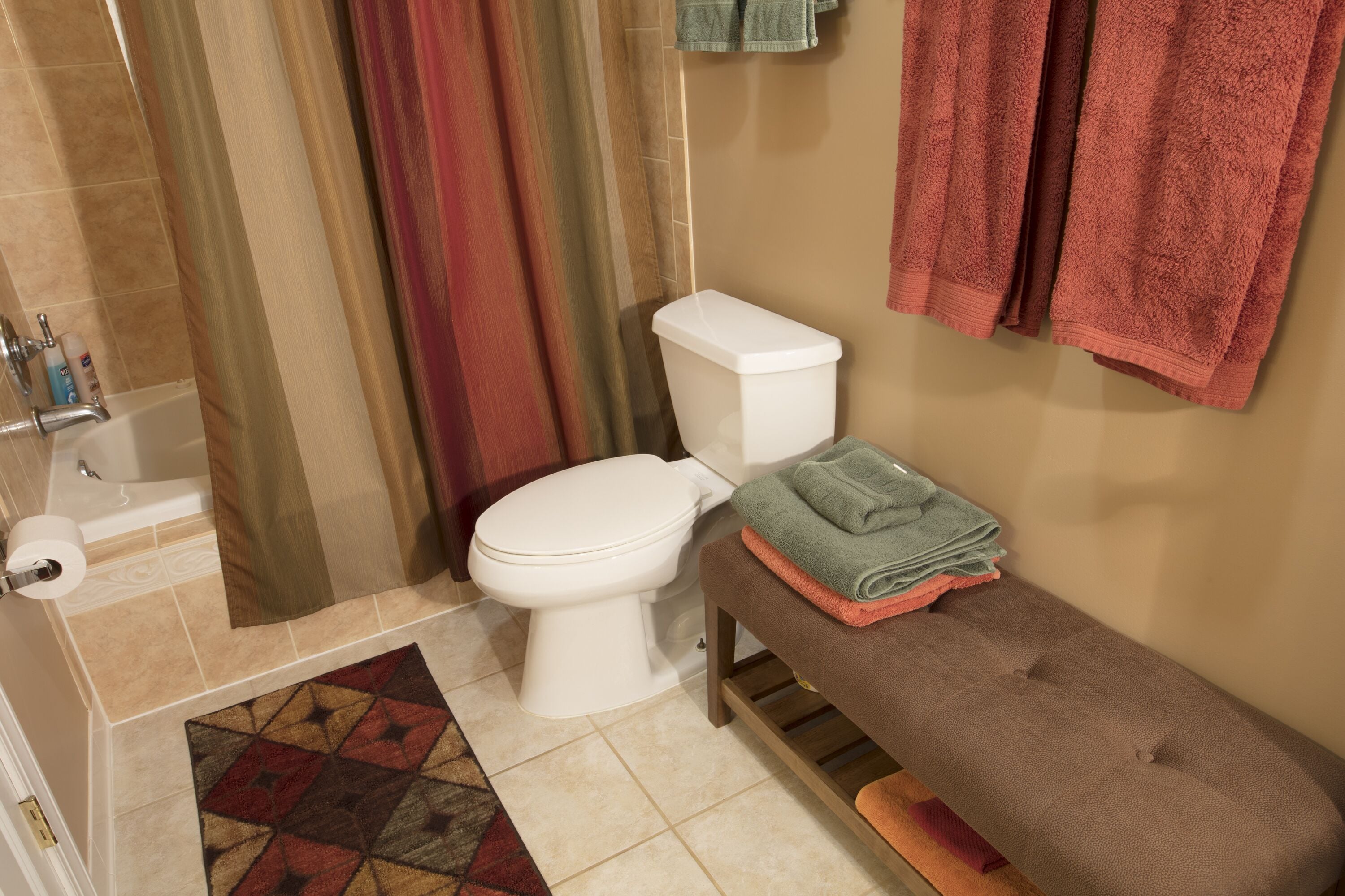 Une salle de bain avec des toilettes, un lavabo et un banc.
