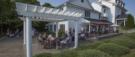 A white building with a covered patio area, outdoor seating, and a small garden.