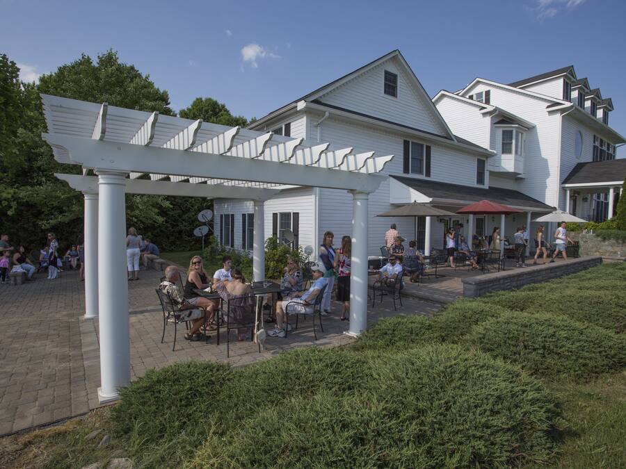 A white building with a covered patio area, outdoor seating, and a small garden.