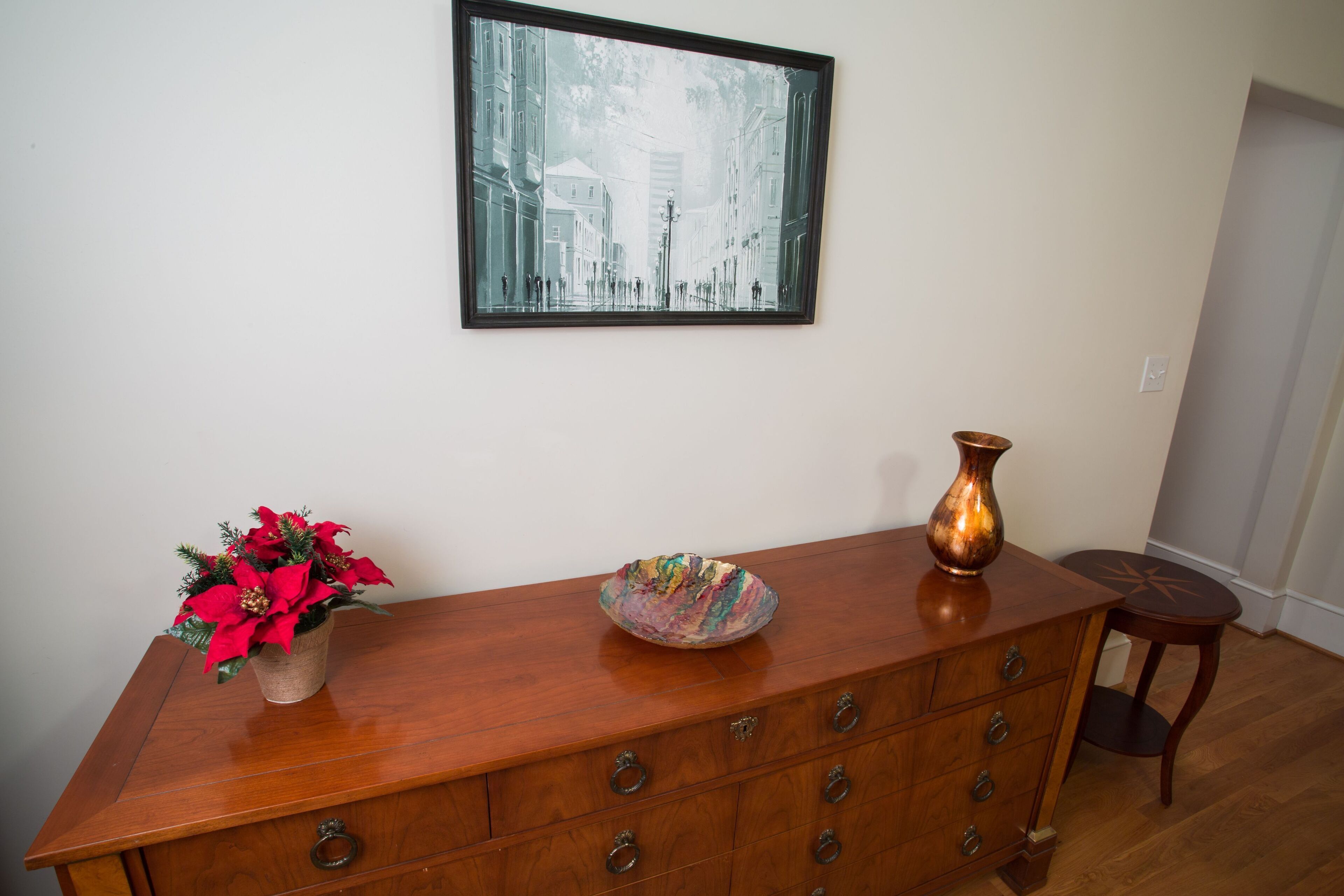 A wooden dresser with multiple drawers, a vase, and a bowl on top.