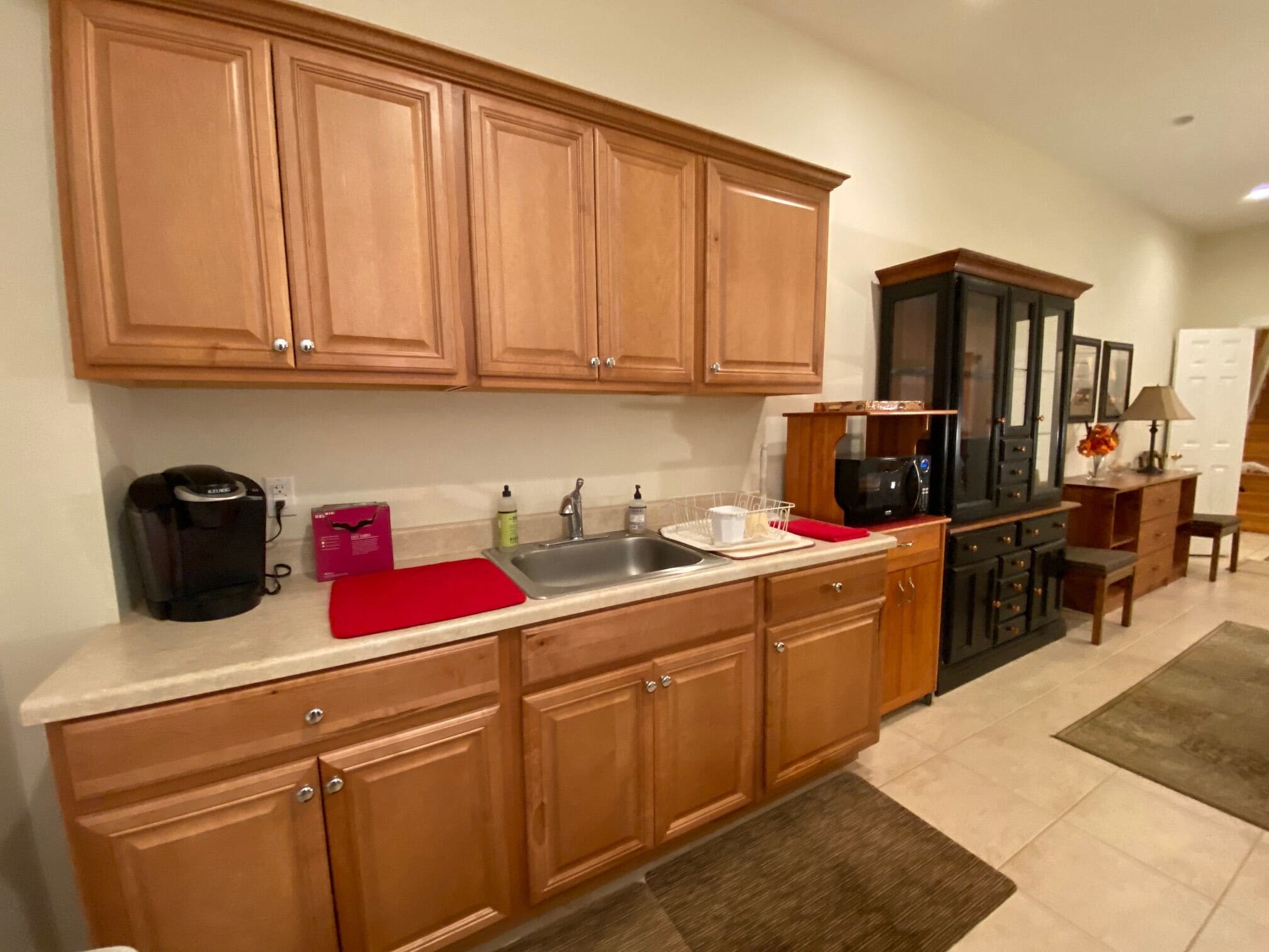 A kitchen with wooden cabinets, a black coffee maker, a red cutting board, and a microwave.