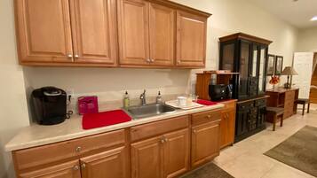 A kitchen with wooden cabinets, a black coffee maker, a red cutting board, and a microwave.