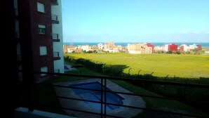 Un edificio residencial con vista a un campo verde y una piscina.