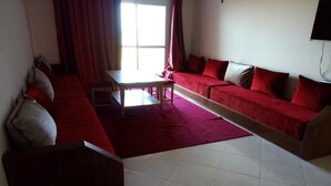 Una sala de estar con un sofá rojo, una mesa de centro de madera y una alfombra roja.
