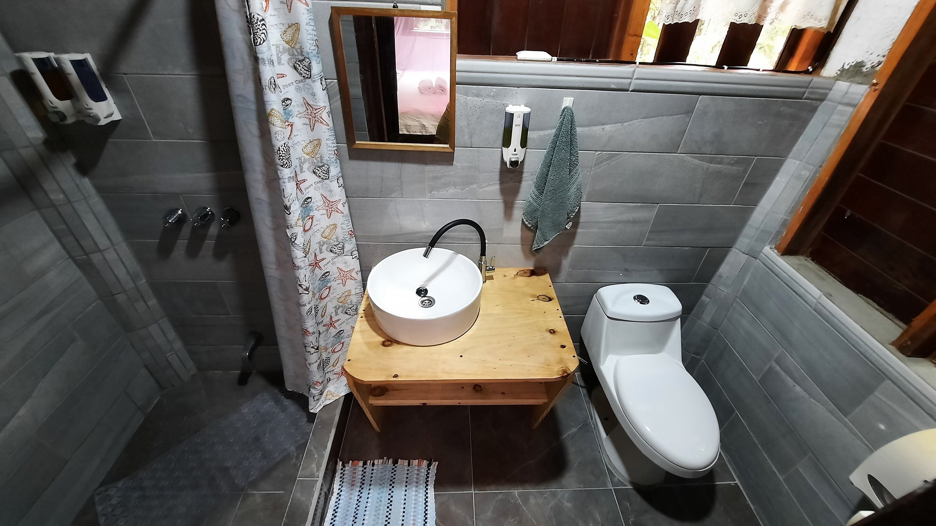 A compact bathroom with a wooden vanity, a white sink, and a toilet.