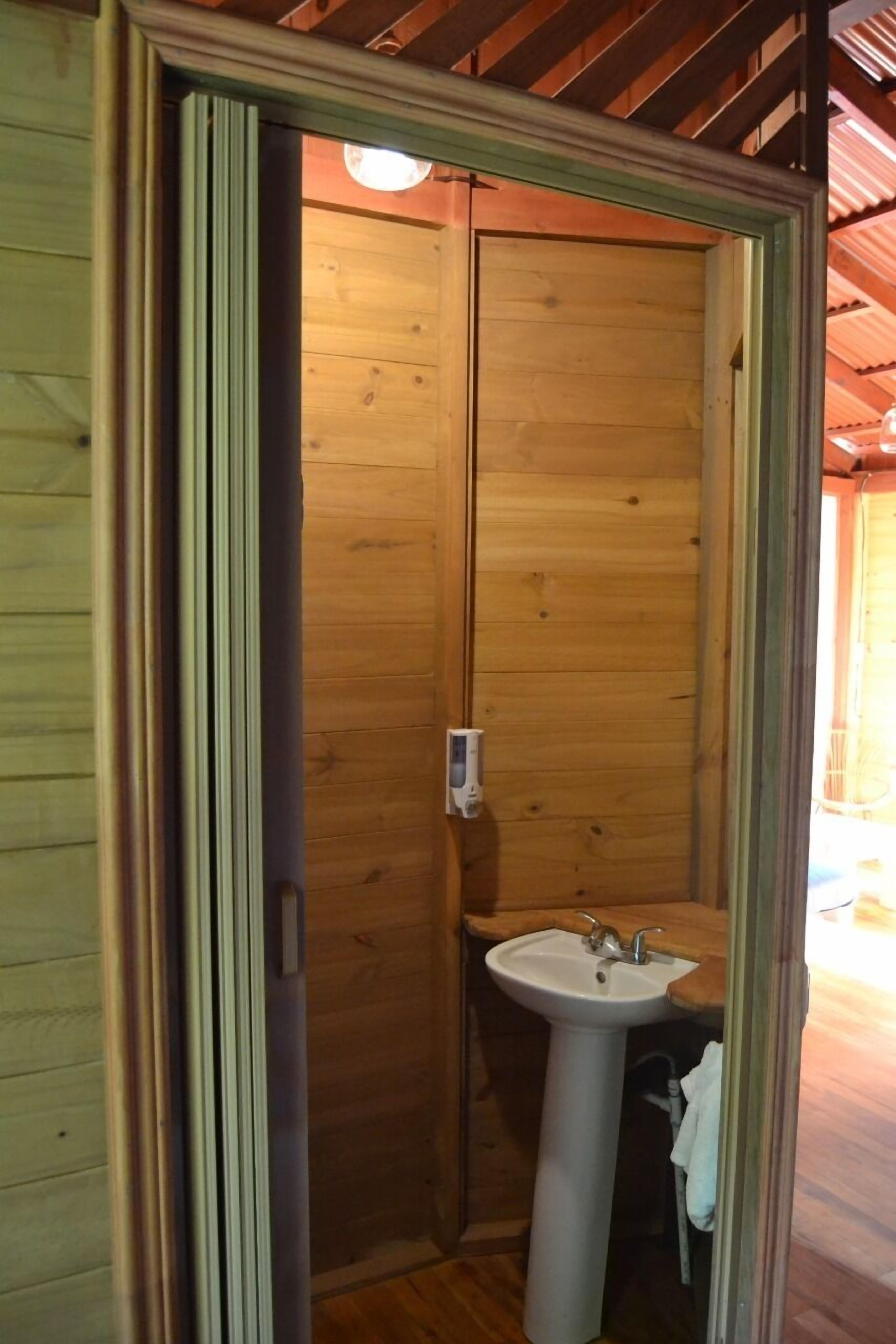 Un baño de madera con un lavamanos y una toalla colgada en la pared.