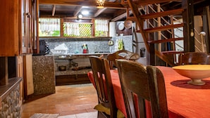 A rustic kitchen with wooden beams, a dining table with chairs, and a hanging light fixture. - Chalet Y Cabinas Hibiscus (Cahuita)