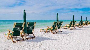 A row of beach chairs and umbrellas on a sandy beach with clear blue water in the background. - Pearl 1001 Completely renovated from floor to ceiling! Super clean!  (Navarre)