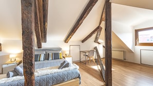 Une chambre avec un lit en mezzanine, des poutres en bois, un bureau et une chaise.