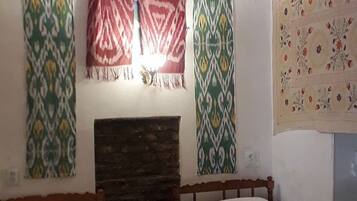 Una habitación con dos camas, un radiador, cortinas estampadas y un aire acondicionado de pared.