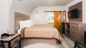 A hotel room with a bed, bedside table with a phone, a TV, and a wooden wardrobe. - Palace Inn - Louetta (Spring)