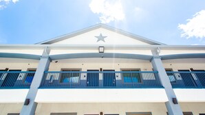 A building with a prominent star on the facade, a balcony with blue railings, and a clear sky in the background. - Palace Inn - Louetta (Spring)