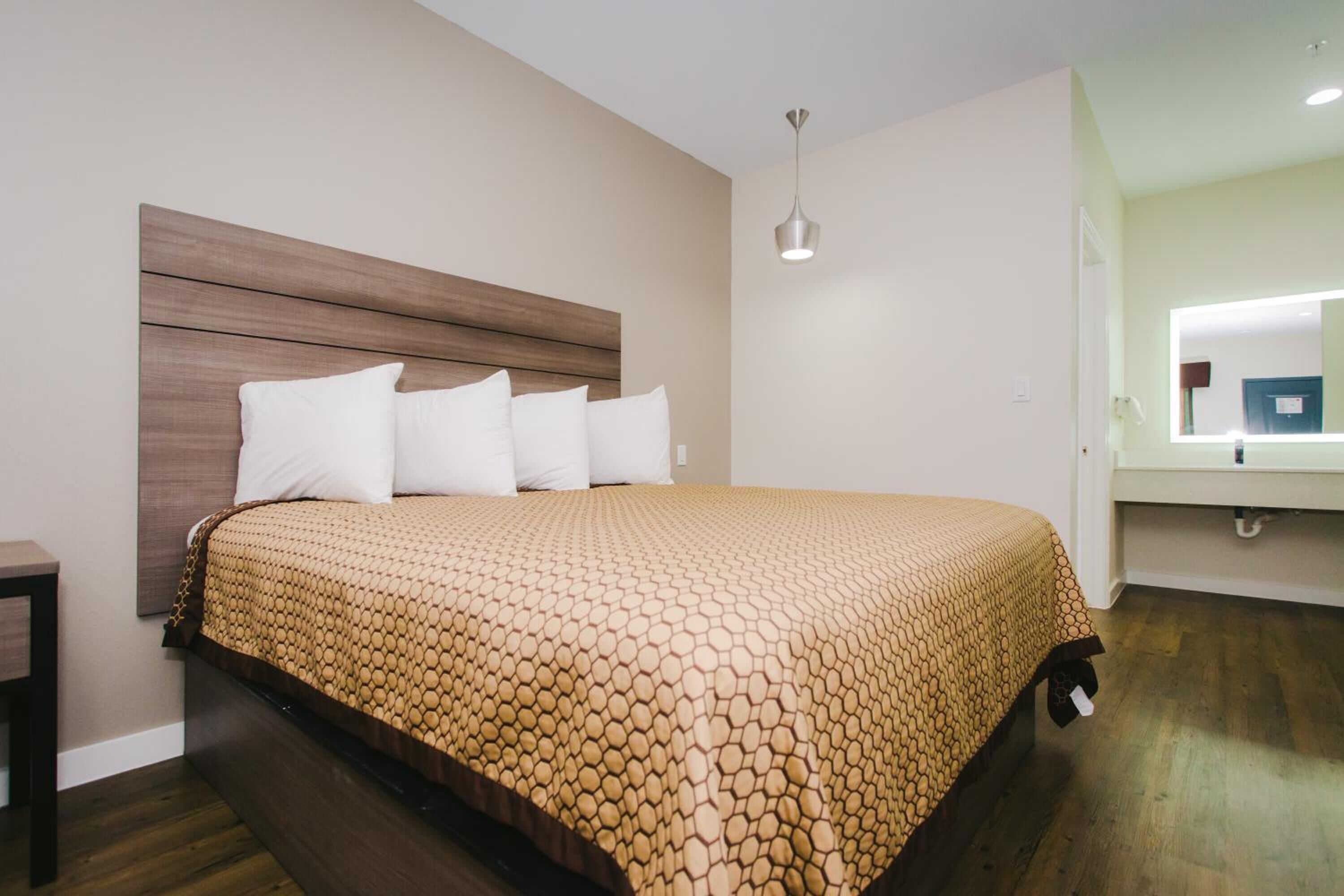 A neatly made bed with a patterned bedspread, a wooden headboard, and a bedside table.