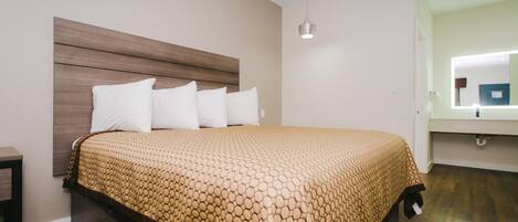 A neatly made bed with a patterned bedspread, a wooden headboard, and a bedside table.