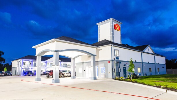 A hotel with a prominent tower, a covered entrance, and a parking lot. - Palace Inn - Louetta (Spring)