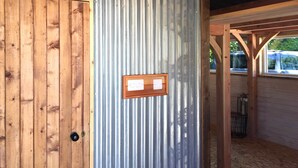 Una puerta de madera con un panel metálico e interruptor de luz en la pared contigua.