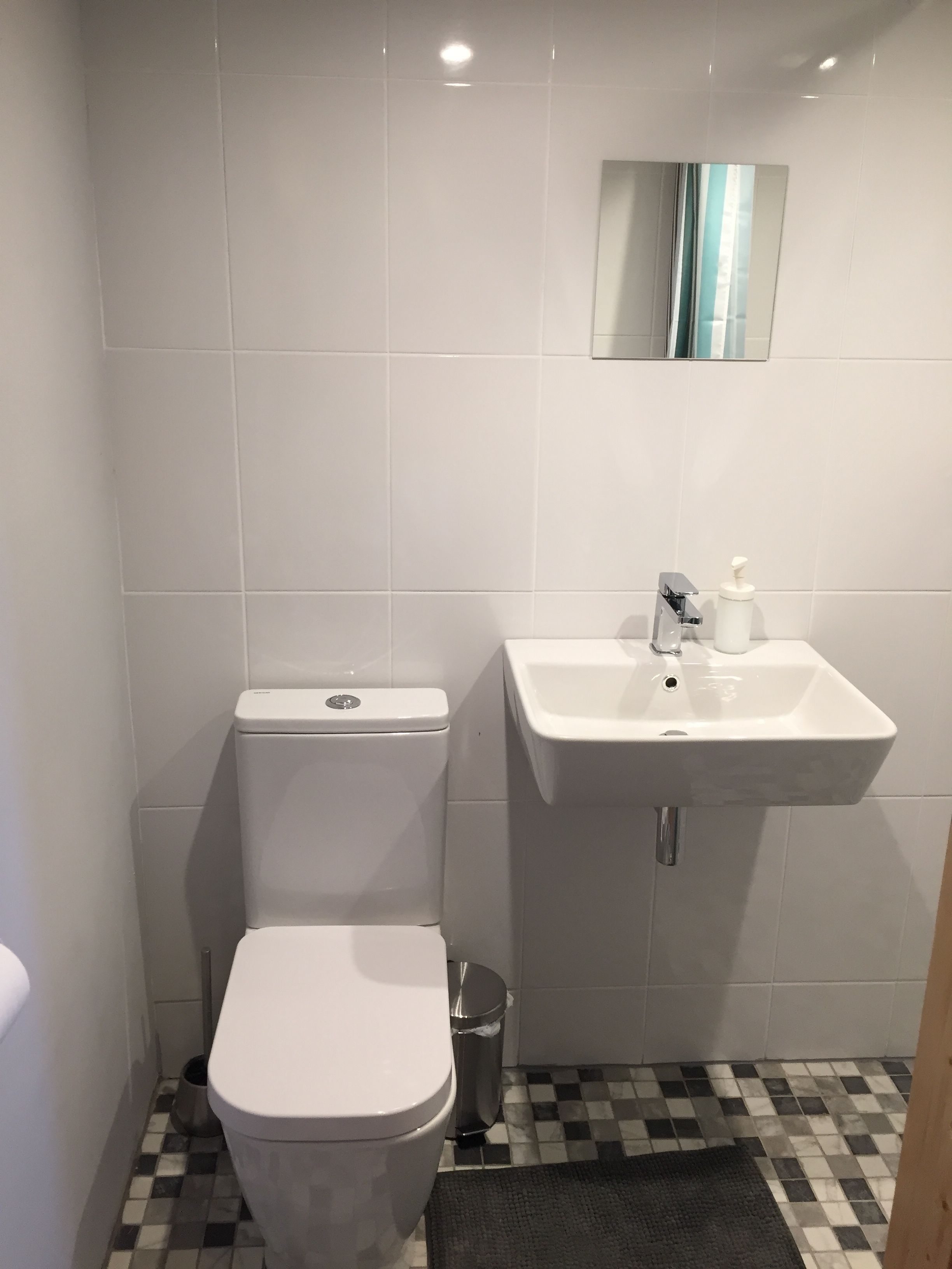 Baño pequeño con inodoro, lavamanos y un cubo de basura.