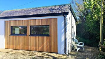 A small, single-story building with a sloped roof, two windows, and a wooden exterior.