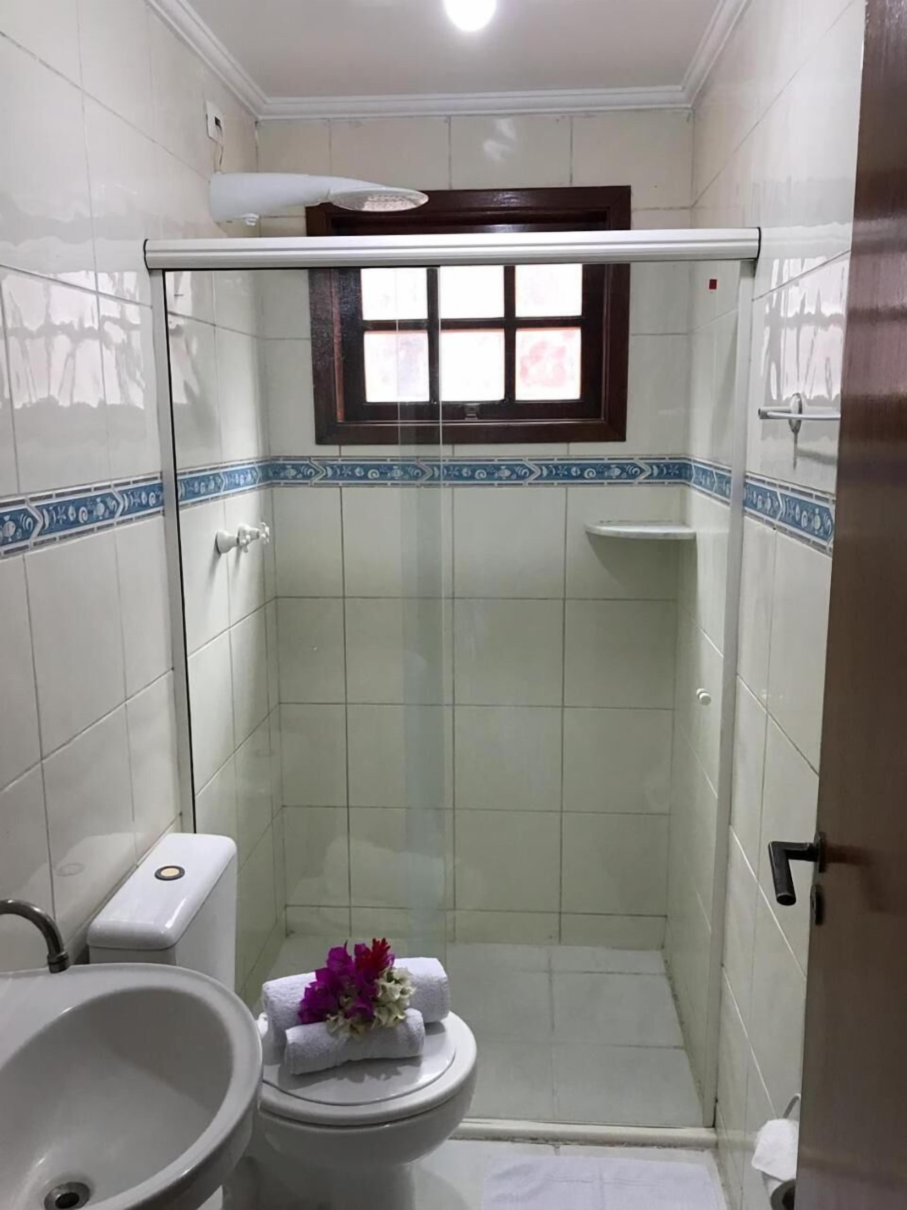 A small bathroom with a shower, toilet, and sink.