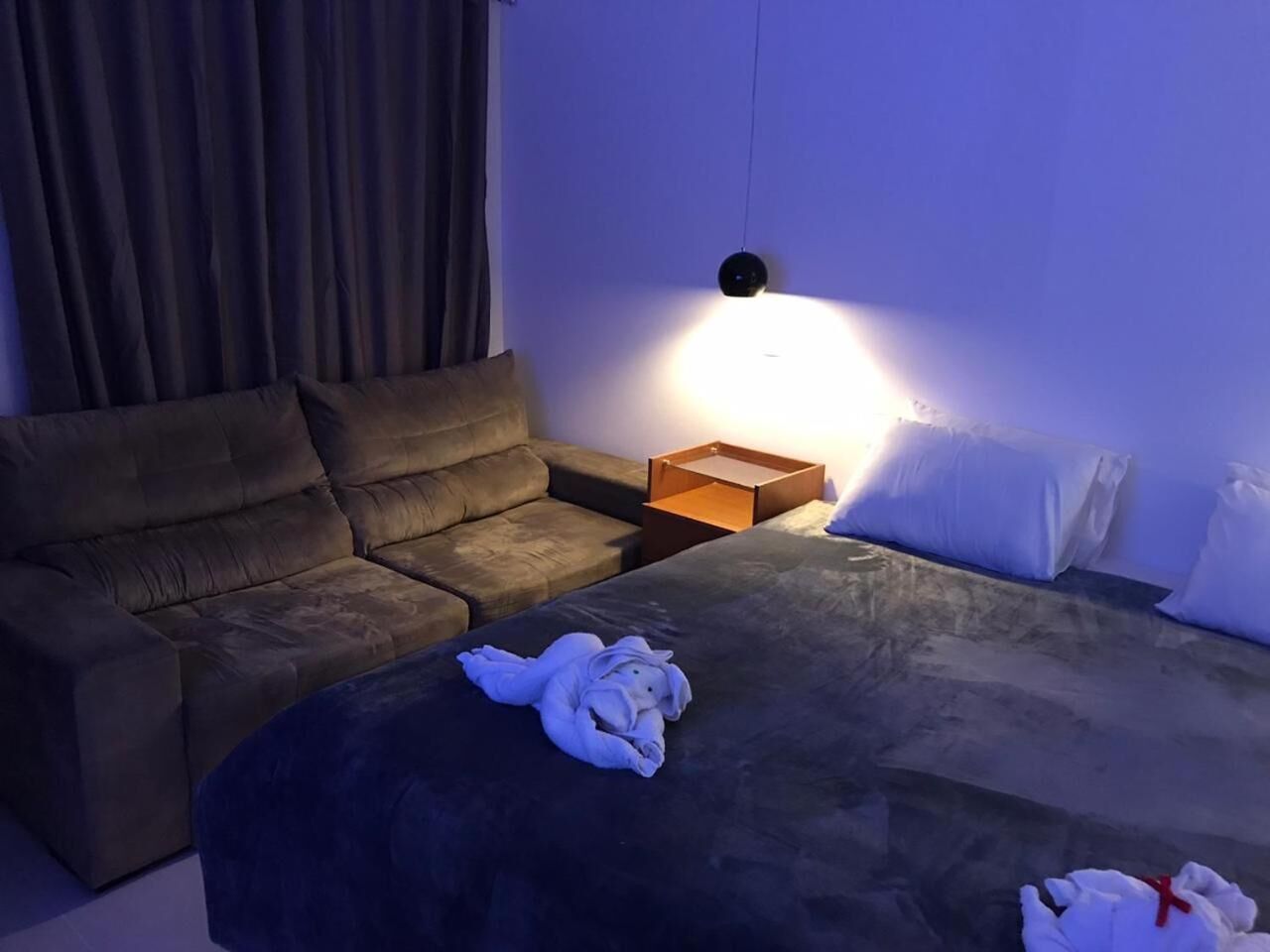 Une chambre d’hôtel avec un lit, un canapé, une table de chevet et une lampe.