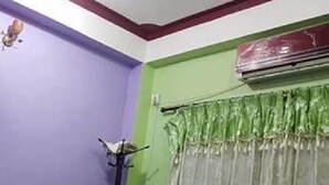Una habitación con paredes moradas, una cortina verde y un equipo de aire acondicionado.