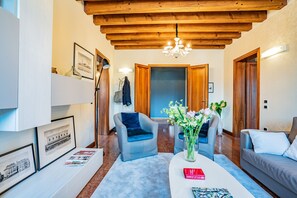 A modern living room with a high wooden ceiling, a chandelier, a sofa, a coffee table, and framed pictures on the wall. - Ca' Del Monastero 6 Collection (Venice)
